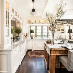 the kitchen is clean and ready for us to use it's white cabinets, wood floors, and counter tops