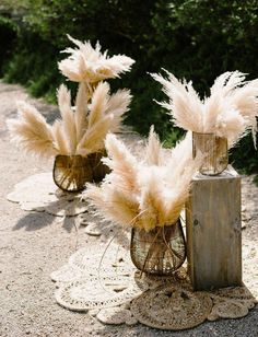 three vases with flowers in them sitting on the ground