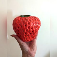 a hand holding a red strawberry shaped object