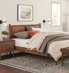 a bed room with a neatly made bed next to a dresser and mirror on the wall