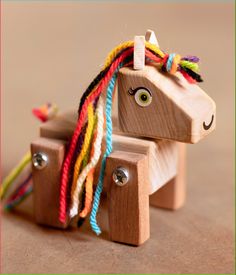 a wooden toy horse with multicolored hair on it's head and eyes