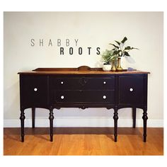 a black dresser sitting on top of a hard wood floor next to a white wall