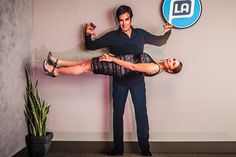 a man and woman are dancing in front of a wall with an ad on it