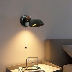 a lamp that is on the side of a wall next to a table with a book