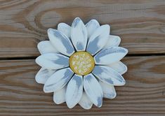 a white and yellow flower sitting on top of a wooden table