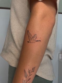 a woman's arm with a bird and flower tattoo on the left side of her arm