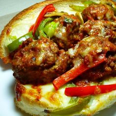 a meatball sandwich with peppers and cheese