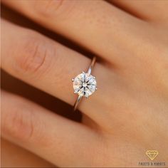 a woman's hand with a diamond ring on top of her finger, showing the center stone