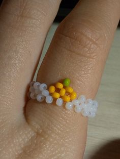 a person's hand with a ring made out of small beads and plastic balls