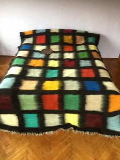 a multicolored blanket sitting on top of a wooden floor