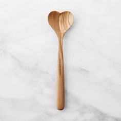 a wooden spoon sitting on top of a white marble counter with a heart shaped handle