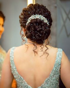 the back of a woman's head wearing a tiara and looking at her reflection in a mirror