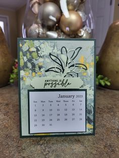 a desk calendar sitting on top of a table next to christmas ornaments and vases