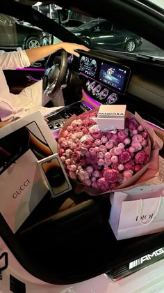 a woman sitting in a car holding a bouquet of flowers and some other items on the floor