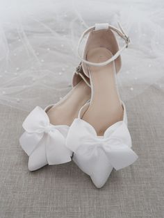 a pair of white shoes with bows on them