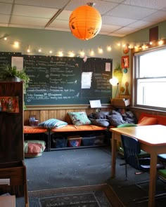 a room with two couches and a chalkboard on the wall behind it that has lights hanging above them