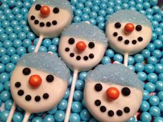 four frosted snowman lollipops sitting on top of blue candies