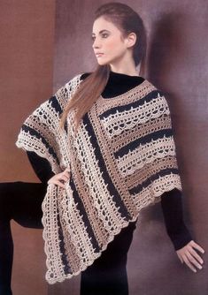 a woman wearing a black and white crochet ponchy shawl standing in front of a wall