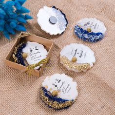 four decorated cookies sitting on top of a table next to blue and gold decorations in a cardboard box