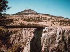 a bridge that is going over some rocks and trees on the side of a mountain