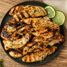 grilled chicken on a black plate with lime wedges