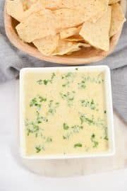 a bowl of tortilla chips next to a plate of guacamole