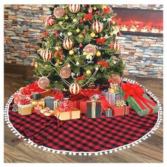 a christmas tree with presents under it in front of a brick wall and plaid tablecloth