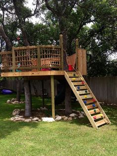 a wooden tree house with a ladder to the top and stairs up to the bottom