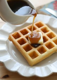 a waffle with syrup being drizzled onto it on a white plate