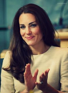 a woman sitting down with her hand up in the air and smiling at the camera