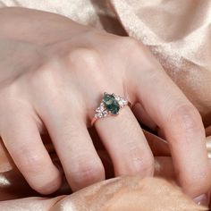 a woman's hand with an emerald and diamond ring