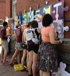 several people are standing in front of a wall that has been decorated with signs and posters