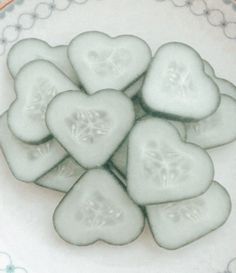 cucumber slices arranged in the shape of hearts on a white and blue plate