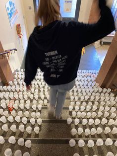 a woman is walking up some stairs with cups on the floor in front of her