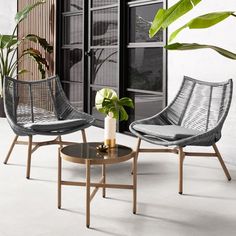 two chairs sitting next to each other in front of a window with plants on it