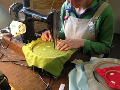 a woman is using a sewing machine to sew on a piece of green fabric