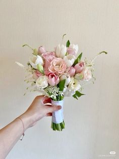 a hand holding a bouquet of pink and white flowers in it's left arm