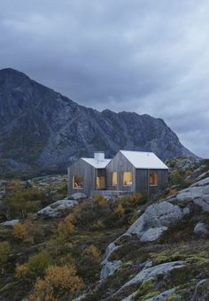 a house on the side of a mountain with mountains in the background