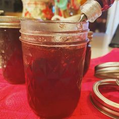 a jar filled with red liquid sitting on top of a table next to two other jars