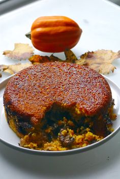 a piece of cake sitting on top of a white plate next to an orange pumpkin