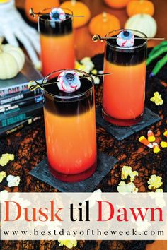 two glasses filled with orange liquid on top of a table next to books and pumpkins