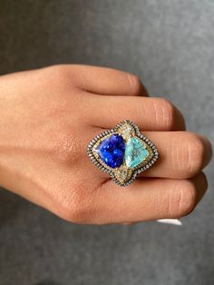 A unique cocktail ring with 5.17 carat natural Tanzanite and 2.66 carat natural Paraiba, with 0.61 carat 2 piece marquise shaped White Diamond and 0.79 carat round cut White Diamond, all set in solid 18K Gold. The rhodium polish in yellow and black, and the contrasting blue color of the trillion shaped gemstones make the cocktail ring a truly statement piece! The ring is currently sized at US 7, can be resized.  18K White Gold : 10.69 Grams  Tanzanite : 5.17 Ctw Paraiba : 2.66 Ctw Diamond : 1.4 Ctw Unique Cocktails, Natural Tanzanite, Blue Band, Yellow And Black, Cocktail Ring, Cocktail Rings, Rings Statement, White Diamond, Laser Engraving