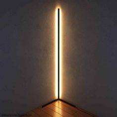 a light that is on the side of a wall next to a floor with a wooden floor