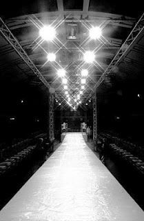 an empty runway with rows of chairs and lights on the ceiling in black and white