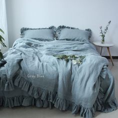 an unmade bed with blue linens and ruffled bedspread