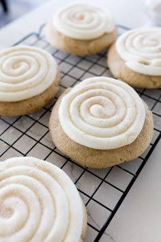 several cookies with white frosting sitting on a cooling rack