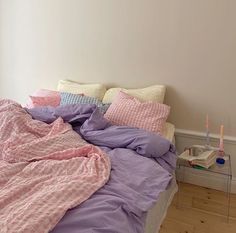 an unmade bed with pink and purple sheets