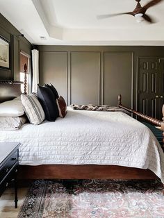 a bedroom with a bed, rug and ceiling fan in the middle of the room