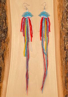 the earrings are decorated with multicolored beads and tassels on wooden plank