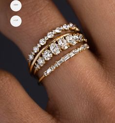 a woman's hand with three gold rings on it and one diamond ring in the middle